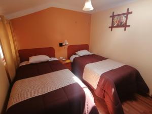 a room with two beds and a cross on the wall at Conquista Cusco in Cusco
