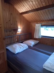 two beds in a room with wooden walls at fraai chalet Barvaux in Durbuy