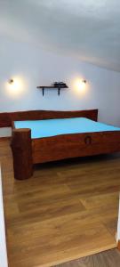 Cama de madera en habitación con suelo de madera en АПАРТАМЕНТ АРГАНТОНЕ, en Sinemorets