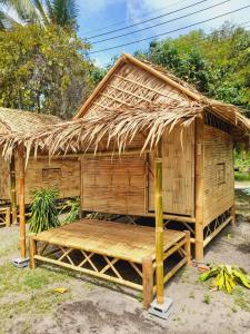 eine strohgedeckte Hütte mit einer Bank davor in der Unterkunft Bamboo Bungalow Baan Tai Phangan in Baan Tai
