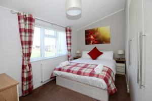 ein Schlafzimmer mit einem Bett mit roten Kissen in der Unterkunft Ryedale Lodge with Hot Tub in Malton