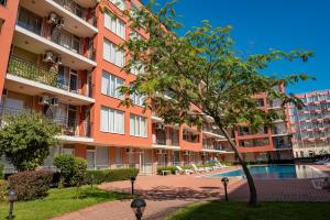 un edificio de apartamentos con piscina y un árbol en Sunset Beach - Menada Apartments en Sunny Beach