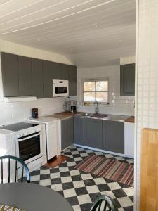 uma cozinha com armários cinzentos e um piso xadrez em Pärla med egen brygga em Västerås