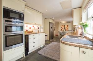 een keuken met witte kasten en een spoelbak bij Gargoyle Cottage in St. Agnes 