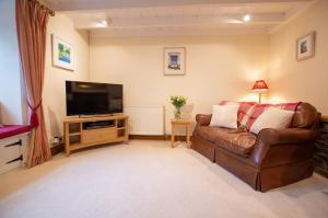 een woonkamer met een bank en een flatscreen-tv bij Gargoyle Cottage in St. Agnes 