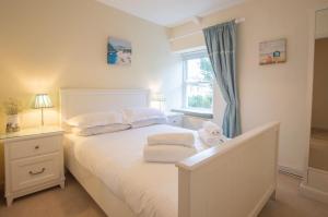 een slaapkamer met een wit bed en een raam bij Gargoyle Cottage in St. Agnes 