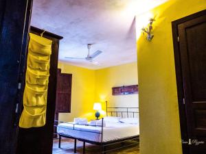 a yellow room with a bed and a lamp at Casa Pizzuta in Noto