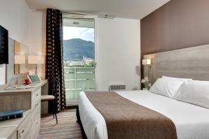 ルルドにあるHôtel Beau Siteのベッドと大きな窓が備わるホテルルームです。