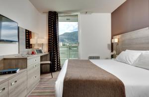 ルルドにあるHôtel Beau Siteの大きなベッドと窓のあるホテルの部屋 +23枚の写真