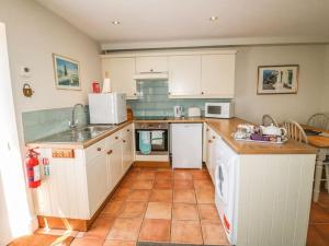 a kitchen with white cabinets and a tile floor at Wetton Barns Holiday Cottages in Ashbourne