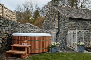 uma banheira de hidromassagem de madeira e uma mesa de madeira num quintal em Little Nut Cottage em Ambleside