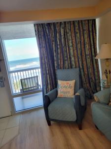 Spectacular Ocean View في دايتونا بيتش: غرفة معيشة مع كرسي ونافذة كبيرة