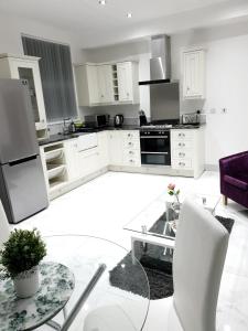 eine Küche mit weißen Schränken und einem Glastisch in der Unterkunft Homebird Property - Conway House in Leeds