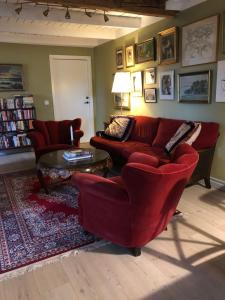 sala de estar con sofá rojo y sillas en Noble Hill en Ängelholm