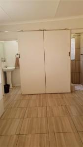ein Badezimmer mit weißen Türen und Holzboden in der Unterkunft Toni's Cottage in Graaff-Reinet