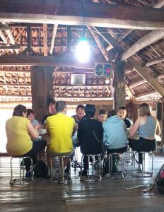 eine Gruppe von Personen, die an einem Tisch in einem Zimmer sitzen in der Unterkunft Homestay Nguyễn Huệ in Làng Mõ
