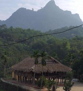 eine Hütte mit einer Palme vor einem Berg in der Unterkunft Homestay Nguyễn Huệ in Làng Mõ