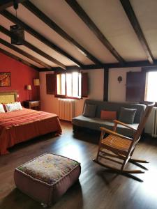 een slaapkamer met een bed, een stoel en een bank bij La Cerca de Torrecaballeros, a 10 min de Segovia in Torrecaballeros