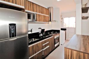 cocina con armarios de madera y nevera de acero inoxidable en 1074 - Apartamento para locação no centro de Bombinhas, en Bombinhas