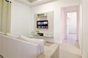 sala de estar blanca con sofá blanco y TV en 1074 - Apartamento para locação no centro de Bombinhas, en Bombinhas