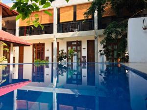 a hotel with a swimming pool in front of a building at Kingcity Resort in Anuradhapura