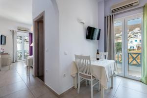 a white dining room with a white table and chairs at Niriides Luxury Studios in Astypalaia