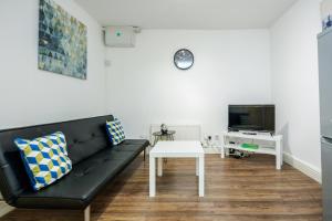 a living room with a black couch and a table at Charming 1-Bed Basement Apartment in Lewisham in London
