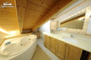 bagno con vasca, lavandino e specchio di Chalet Lucky Exlusive Chalet a Livigno