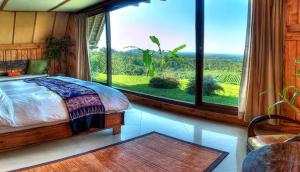 a bedroom with a bed and a large window at Village Above The Clouds in Bedugul