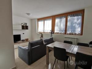 a living room with a table and a couch at Spazioso trilocale sulle piste da sci in Folgarida