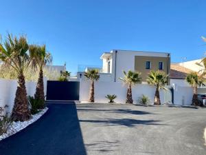una casa con palmeras frente a una entrada en VILLA D’ARCHITECTE À 400M DE LA PLAGE, en Cap d'Agde