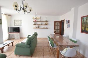 uma sala de estar com uma mesa de madeira e cadeiras verdes em Casa Emiliano em Cee