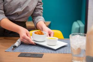 a person sitting at a table with a bowl of food at voco Times Square South New York, an IHG Hotel in New York