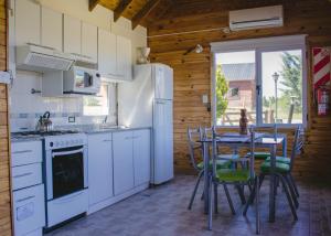 a kitchen with a table and a white refrigerator at Cabañas Rincones del Sur in Trevelín