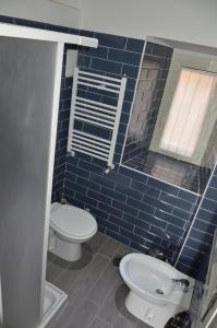 La salle de bains est pourvue de carrelage bleu, de toilettes et d'un lavabo. dans l'établissement Un Caffè sul Balcone 2, à Rome