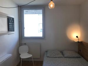 um quarto com uma cama, uma cadeira e uma janela em Chambre paisible tout confort em Courcouronnes