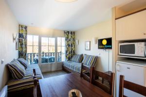 a living room with a couch and a microwave at Résidence Les Belles Rives - maeva Home in Argentat