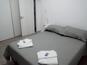 - une chambre avec un lit et des serviettes dans l'établissement Departamento Ezeiza- ciudad de Tandil, à Tandil