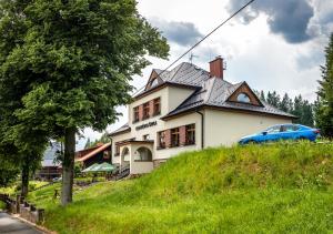 una casa en una colina con un coche azul delante en Bezručova škola en Staré Hamry