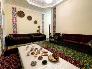 a living room with couches and a table with food on it at Deshon Qala Guest House in Khiva
