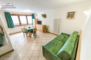 Una sala de estar con un sofá verde y una mesa. en Baita Epi Cusini by Livigno Accomodation, en Livigno