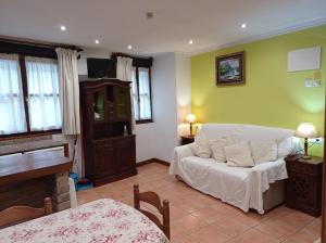 a living room with a bed and a piano at Apartamentos Begoña in Llanes