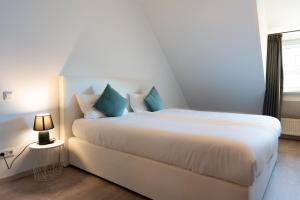 a bedroom with a large white bed with blue pillows at La Fleur Appartement in Überlingen