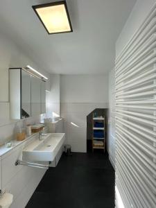 Baño blanco con lavabo y espejo en komfortable Ferienwohnung in Halle-Kröllwitz en Kröllwitz