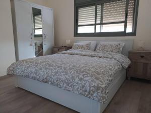 a bedroom with a large bed with a comforter and a window at Beautiful home on the dead sea! in Ovnat