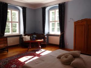 a bedroom with a bed and a chair and windows at Schloss Triestewitz in Arzberg