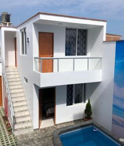 a white house with a swimming pool in front of it at Bravo Surf Camp Punta Rocas in Punta Negra