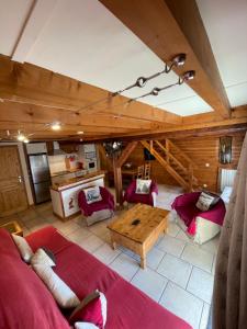 una sala de estar con muebles de color rojo y techo de madera. en Le CHAL HEUREUX bel appartement dans vieille ferme de montagne rénovée en Les Orres