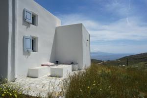 un edificio blanco con dos bancos en una colina en Serifos cozy home with a view, en Livadakia