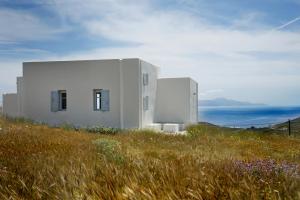 una casa blanca en una colina con un campo de flores en Serifos cozy home with a view, en Livadakia